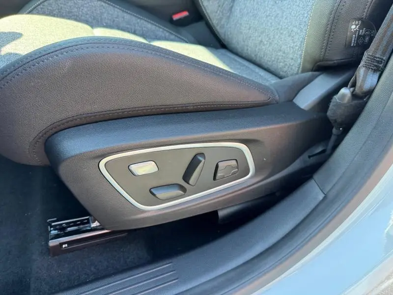 Gros plan sur les commandes de réglage électrique du siège avant côté conducteur du Renault Austral blanc nacré.
