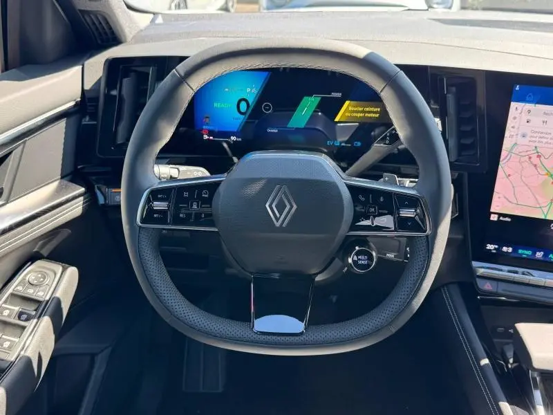 Vue intérieure centrée sur le volant multifonction noir du Renault Austral 2025 avec tableau de bord numérique et écran tactile latéral.