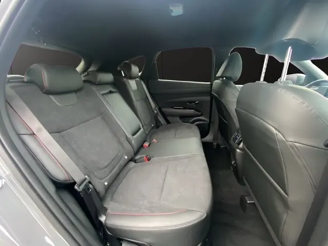 Vue intérieure arrière côté gauche du Hyundai Tucson 1.6 Hybrid gris foncé, sièges en cuir et alcantara avec surpiqûres rouges.