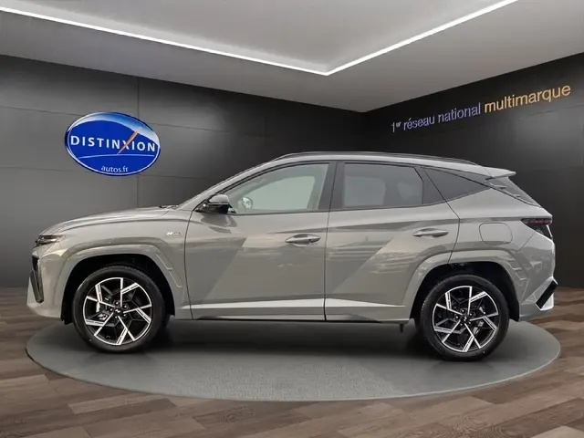 Vue latérale droite du Hyundai Tucson 1.6 Hybrid gris foncé avec jantes alliage et hayon motorisé en showroom.
