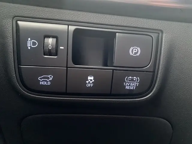 Gros plan sur les commandes intérieures du Hyundai Tucson 2026, boutons de frein à main électrique et ouverture hayon.