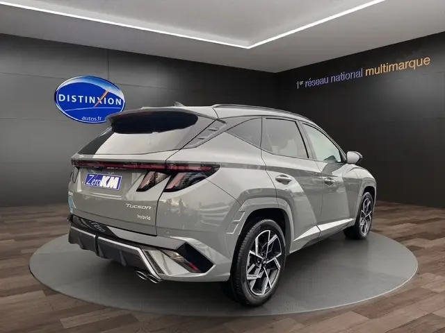 Vue 3/4 arrière d’un Hyundai Tucson 1.6 Hybrid gris foncé avec hayon motorisé et jantes alliage modernes.