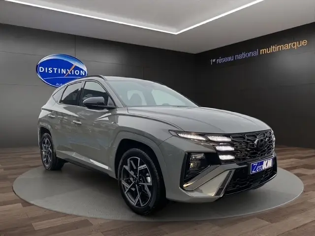 Vue 3/4 avant d’un Hyundai Tucson gris foncé 2026 avec calandre distinctive et jantes alliage noires.