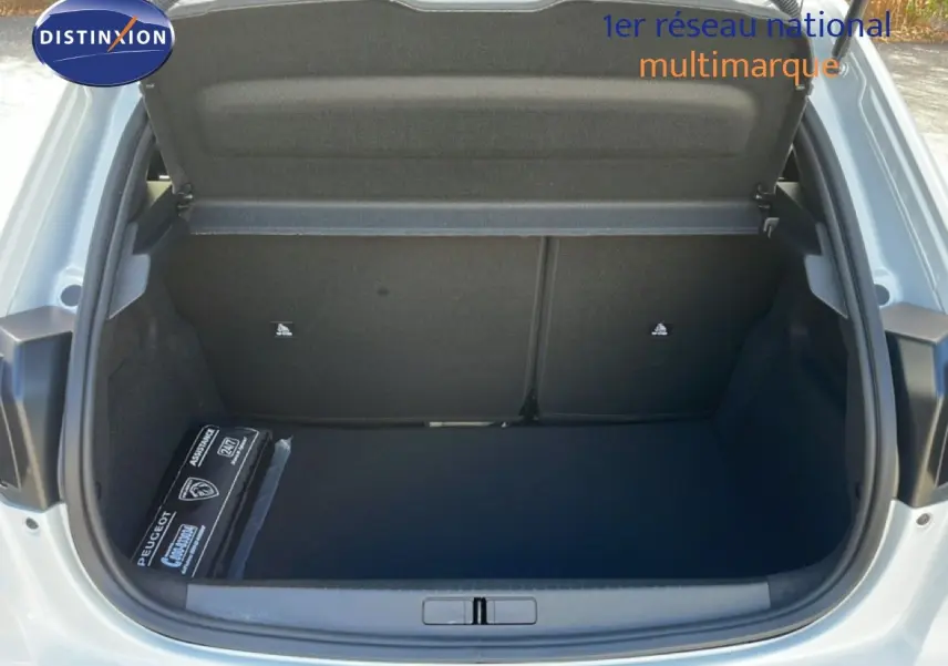 Coffre ouvert vu de l'arrière d'une Peugeot 208 blanche Okenite Metal, montrant un espace de rangement vide et propre.