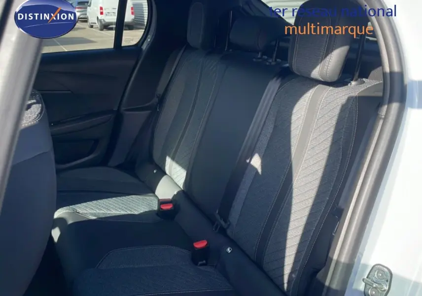Vue intérieure sur les sièges arrière en tissu gris et noir d'une Peugeot 208 Hybrid blanche, porte arrière ouverte.