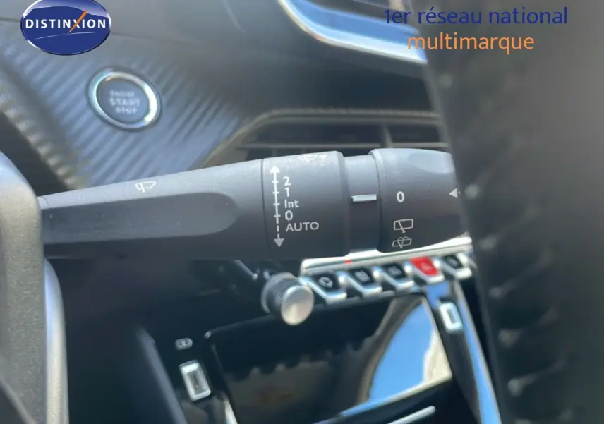 Gros plan sur la commande d’essuie-glace et le bouton start du tableau de bord intérieur d’une Peugeot 208 blanche.