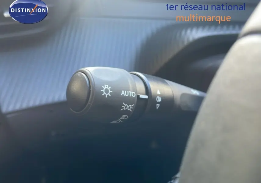 Gros plan sur le commodo des phares à gauche du volant dans l’habitacle d’une Peugeot 208 blanche 2026.