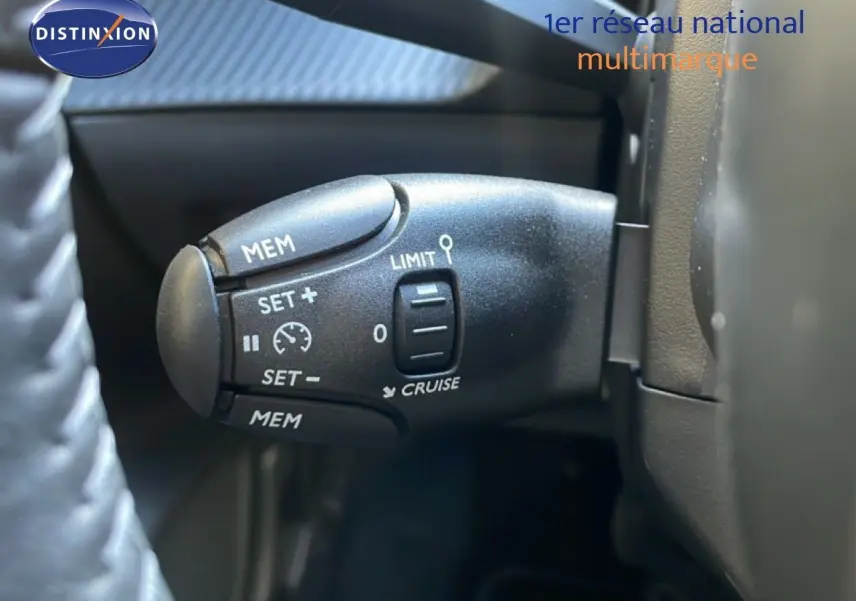 Gros plan sur la commande de régulateur de vitesse au volant d’une Peugeot 208 Hybrid 110ch blanche.
