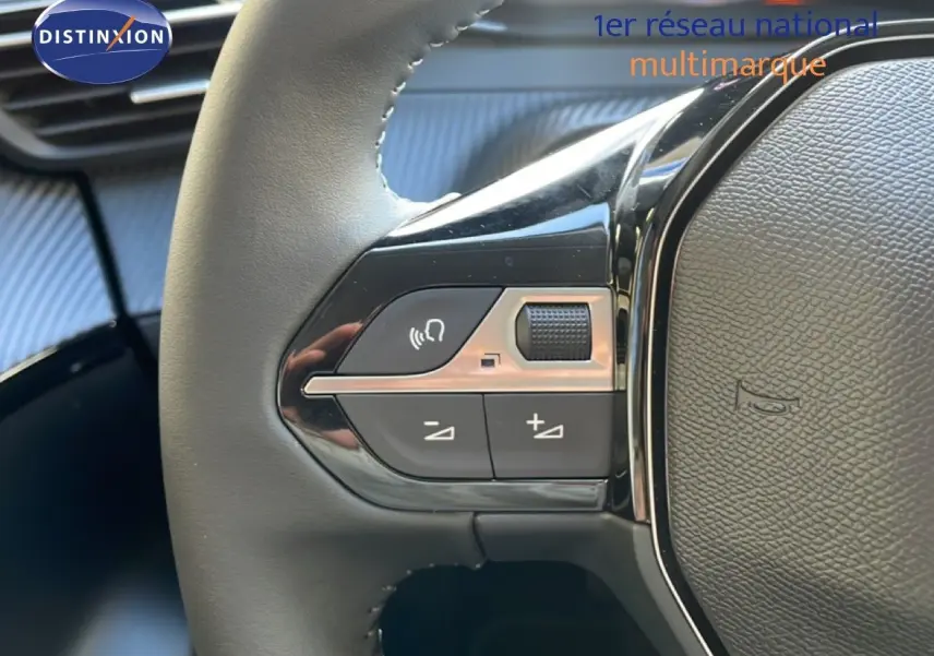 Gros plan sur les commandes gauche du volant noir d’une Peugeot 208 Hybrid blanche, avec boutons de volume et commande vocale.