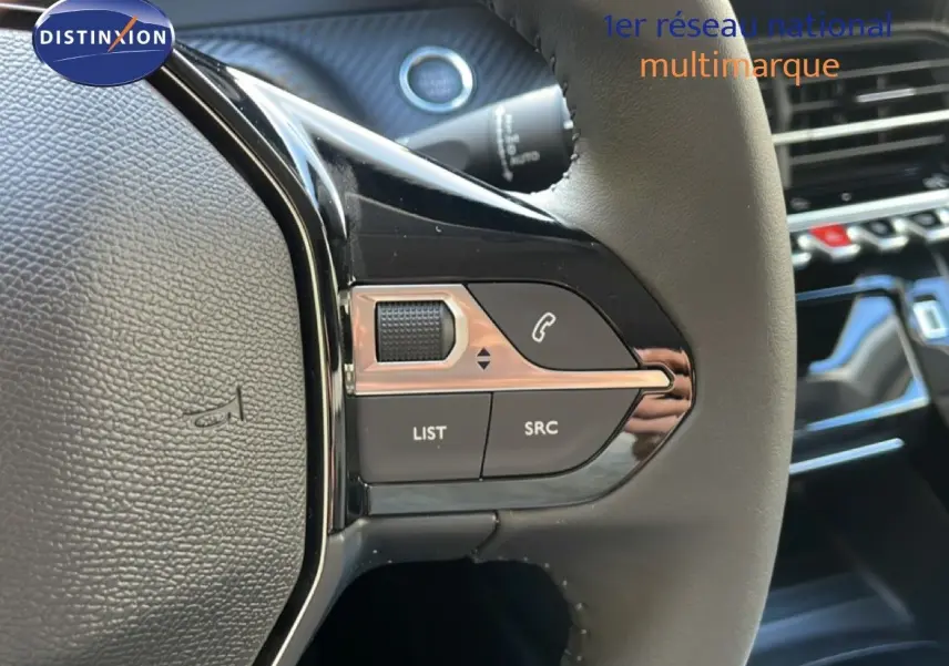 Gros plan sur les commandes gauche du volant en cuir noir du Peugeot 208 Hybrid blanc, avec boutons multifonctions et molette.