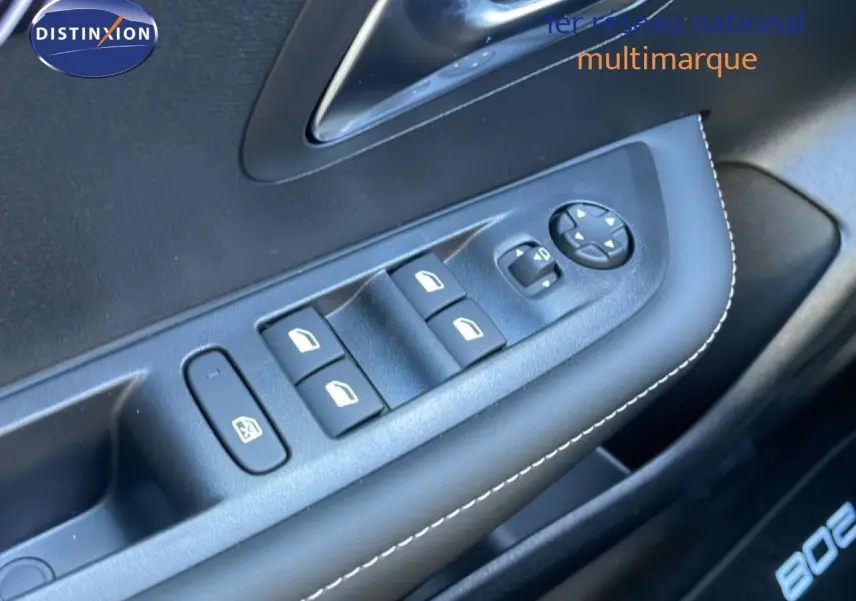 Gros plan sur les commandes de lève-vitres et rétroviseurs côté conducteur d’une Peugeot 208 blanche hybride 2026.
