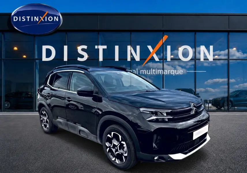 Citroën C5 Aircross noir en 3/4 avant droit, avec jantes alu distinctives et barres de toit visibles.