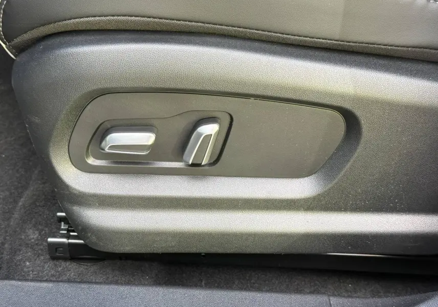 Gros plan sur les commandes électriques de réglage du siège conducteur en cuir synthétique noir du JAECOO J5 Phantom Grey.