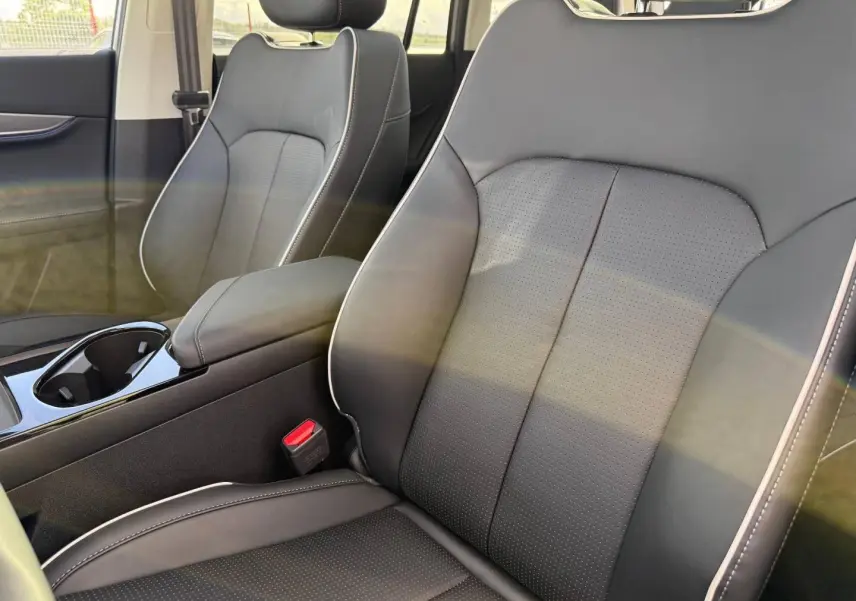 Gros plan sur les sièges avant en cuir synthétique noir avec surpiqûres blanches et accoudoir central dans un JAECOO J5 Phantom Grey.