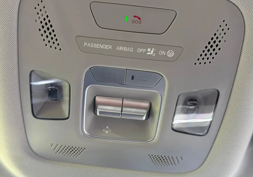 Vue en contre-plongée du panneau de commandes au plafond du JAECOO J5, avec éclairage intérieur et bouton SOS visible.