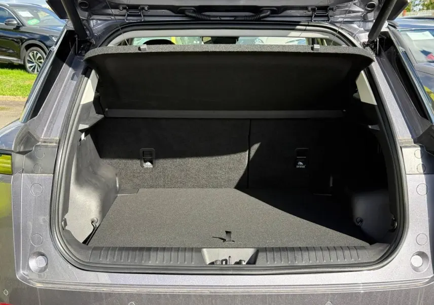 Coffre ouvert d’un JAECOO J5 Phantom Grey métal vu de l’arrière, montrant l’espace de chargement vide et la tablette cache-bagages.