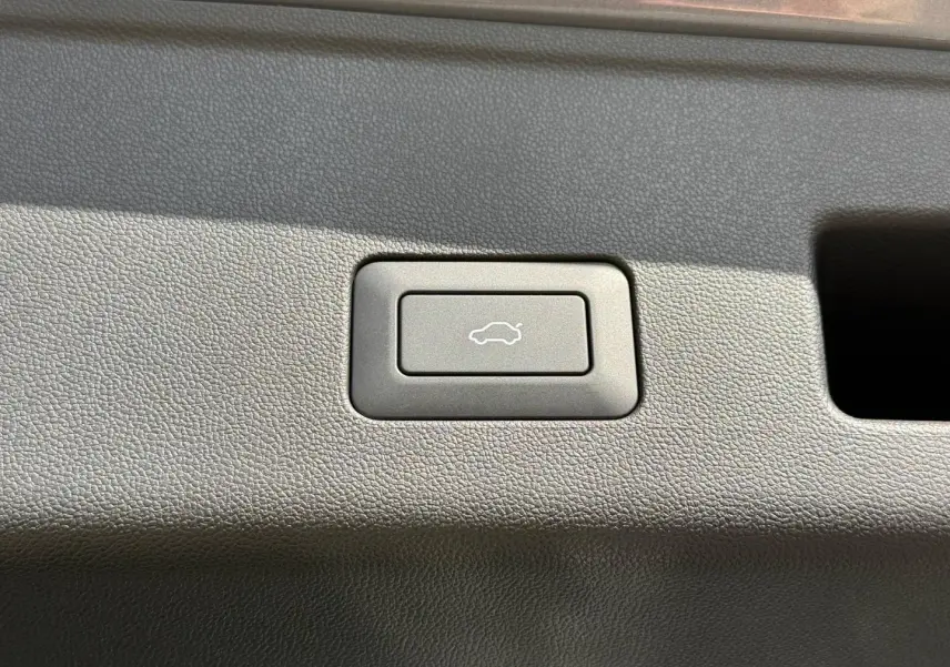 Bouton d'ouverture électrique du coffre sur panneau intérieur en plastique gris du JAECOO J5 Phantom Grey métal.