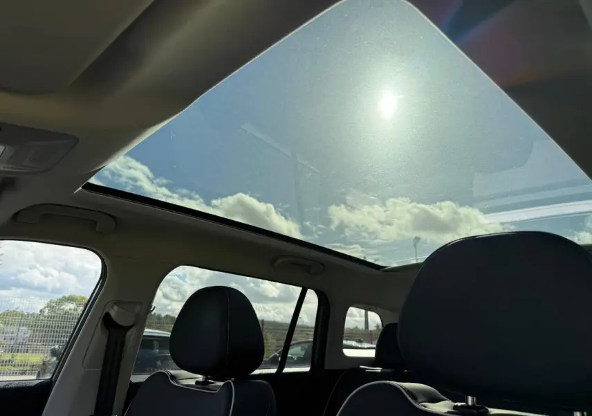 Vue intérieure du toit panoramique en verre du JAECOO J5 Phantom Grey, avec sièges avant en cuir noir visibles de côté gauche.
