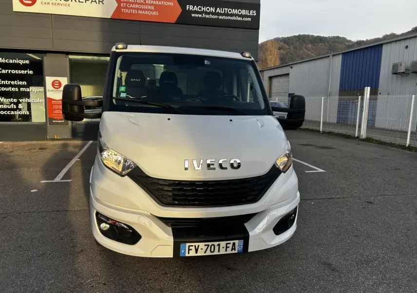 Vue de face d'un utilitaire Iveco Daily blanc immatriculé en France, stationné devant un garage Eurorepar.