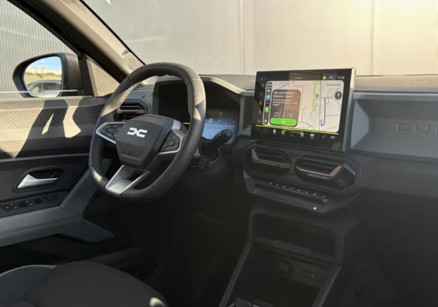 Vue intérieure côté conducteur du Dacia Duster 2026, avec tableau de bord digital et écran tactile GPS lumineux.