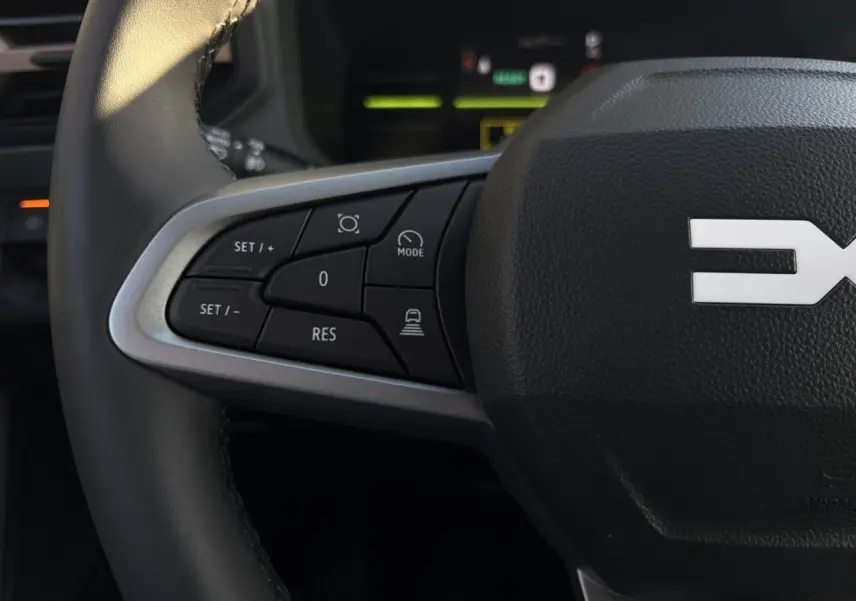 Gros plan sur le côté gauche du volant noir du Dacia Duster 2026 avec commandes de régulateur de vitesse.