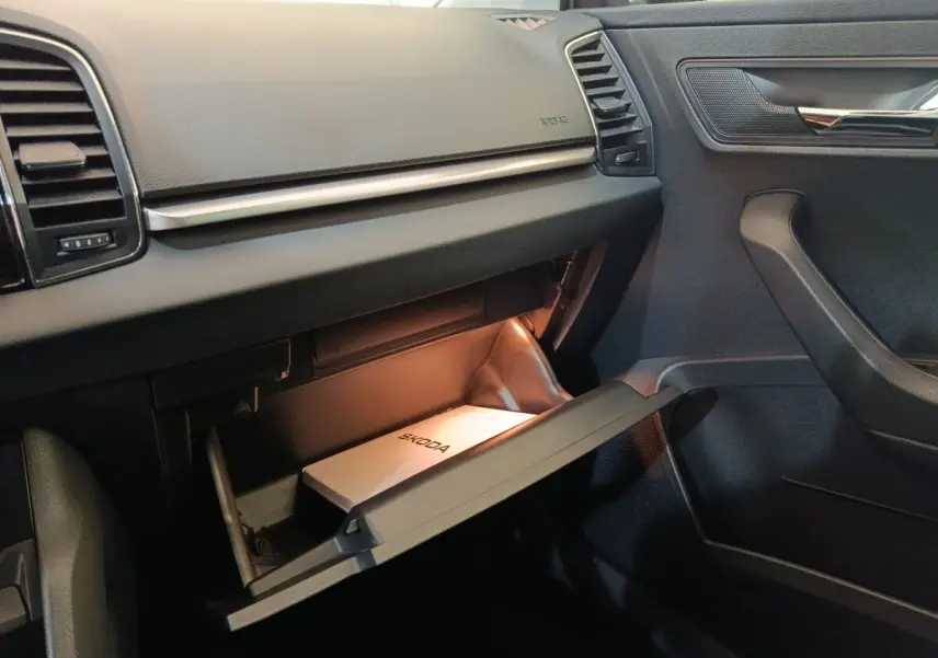 Vue rapprochée de la boîte à gants ouverte côté passager dans l'habitacle noir du Skoda Karoq blanc 2024.
