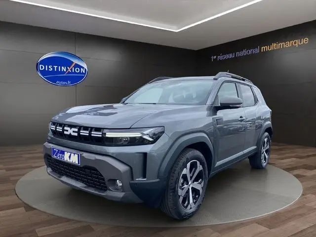 Dacia Duster 2025 gris schiste en 3/4 avant droit, avec jantes alliage et calandre distinctive LED.