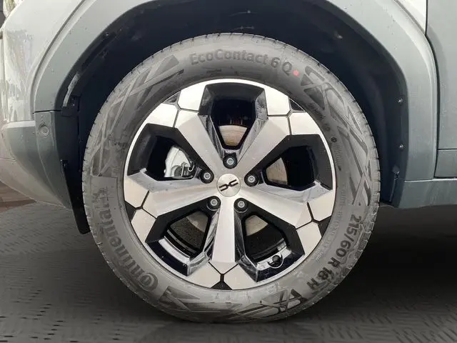 Gros plan sur l'arrière droit du Dacia Duster gris schiste, mettant en valeur la roue de secours et l'aile robuste.