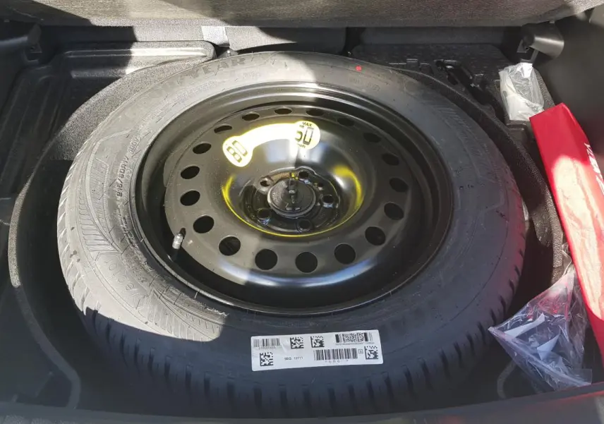 Gros plan sur la roue de secours noire dans le coffre du Jeep Compass blanc 2024 e-Hybrid Altitude.