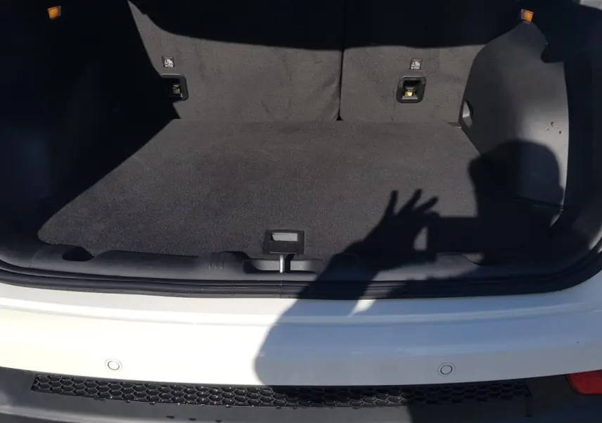 Coffre ouvert vu de l'arrière d'un Jeep Compass blanc 2024, montrant l'espace de chargement vide et tapis noir.