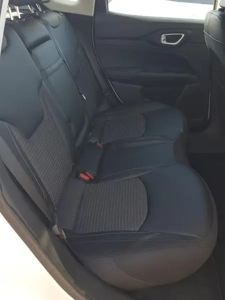 Vue intérieure côté gauche des sièges arrière noirs du Jeep Compass 2024 blanc, avec ceinture et appuie-têtes visibles.