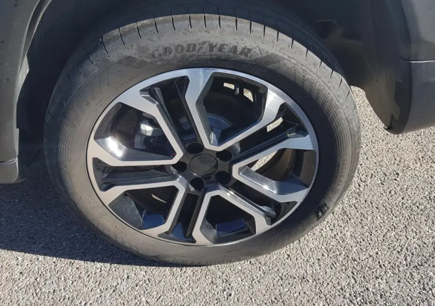 Gros plan sur la jante alliage 18 pouces noire et argent du côté avant droit d'un Jeep Compass blanc.