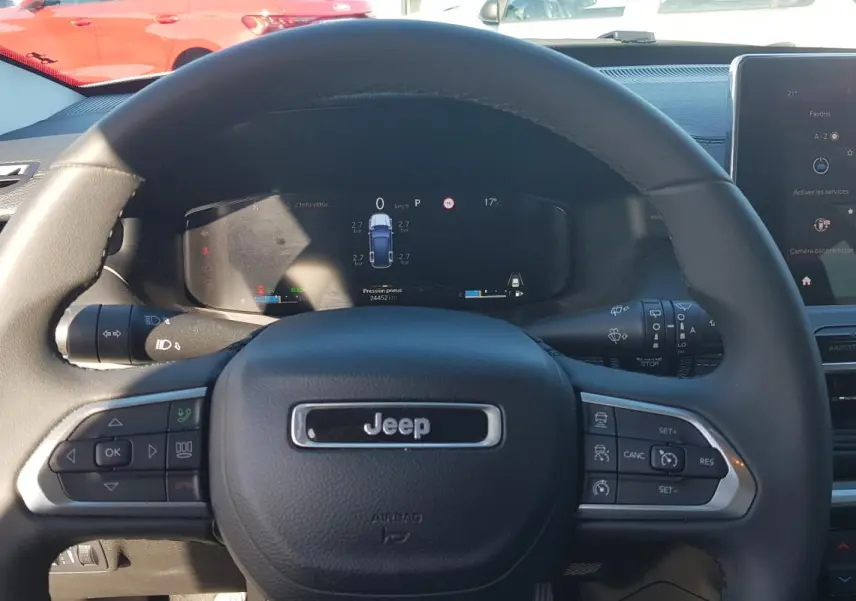 Vue rapprochée du volant Jeep Compass 2024 avec commandes intégrées et tableau de bord numérique allumé.