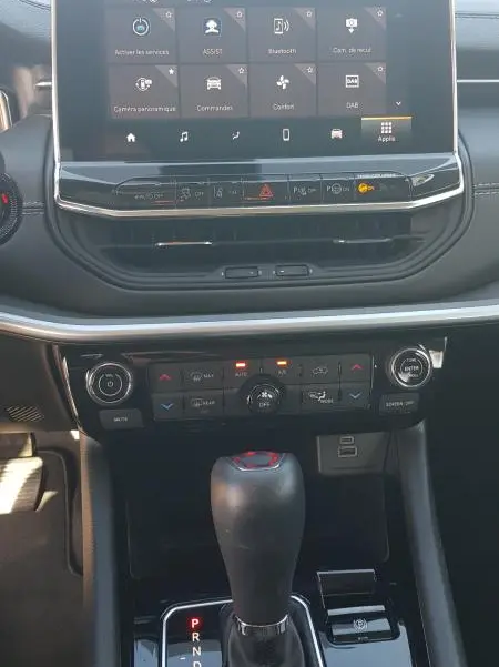 Vue rapprochée de la console centrale du Jeep Compass 2024 avec écran tactile, commandes climatisation et levier de boîte automatique.