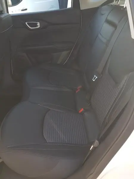 Vue intérieure côté gauche des sièges arrière noirs du Jeep Compass blanc 2024 avec ceinture de sécurité visible.