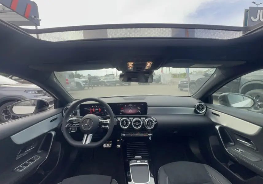 Vue intérieure avant de la Mercedes Classe A 200D BVA Exclusive Design 2026 avec tableau de bord noir et toit ouvrant panoramique.