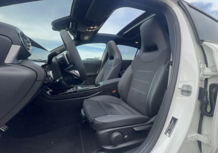 Vue intérieure côté conducteur d'une Mercedes Classe A 200D Exclusive Design blanche avec sièges sport noirs et toit ouvrant panoramique.