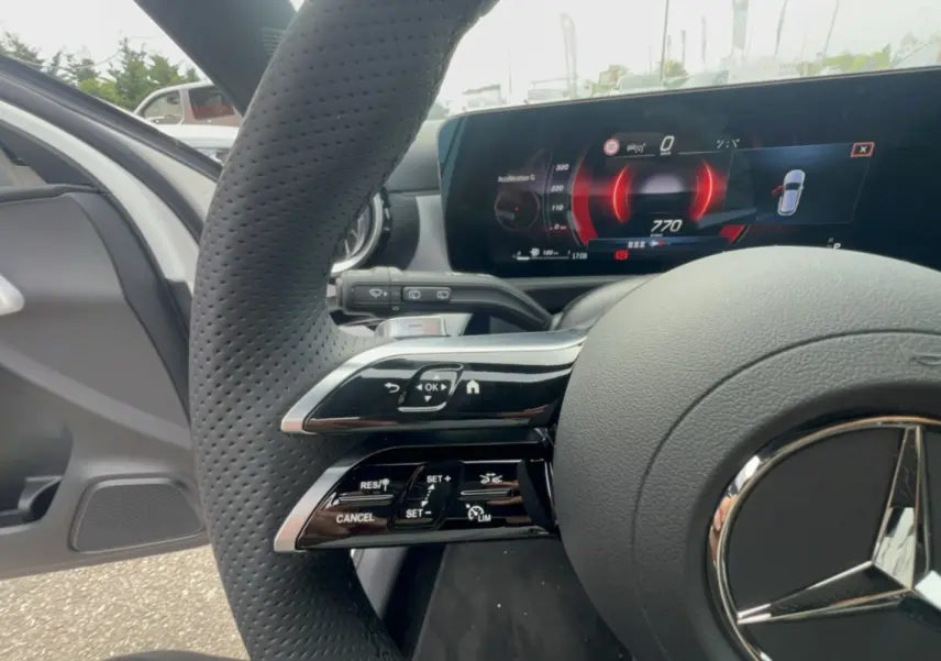 Gros plan sur le volant cuir multifonctions et le tableau de bord numérique de la Mercedes Classe A 200D blanc polaire.