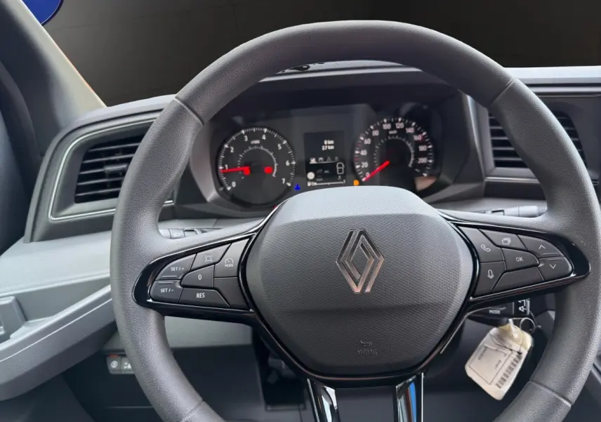 Vue rapprochée du volant multifonctions gris du Renault Master 2026 avec tableau de bord numérique en arrière-plan.