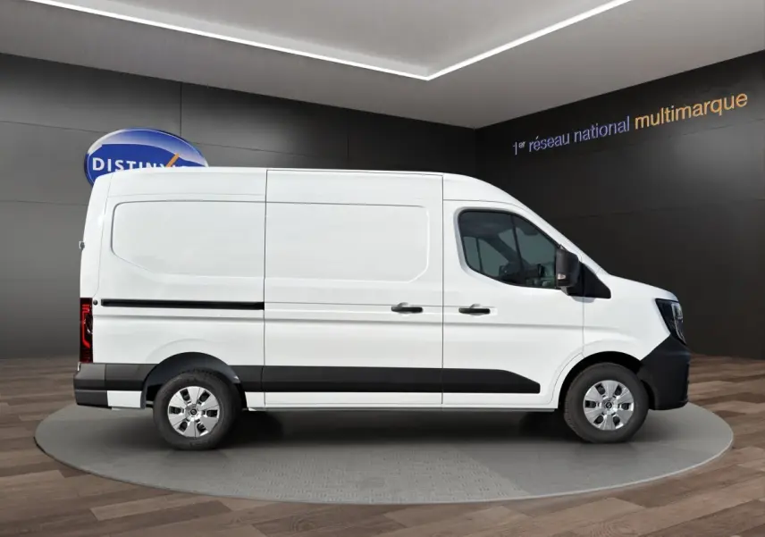 Vue de profil côté droit du Renault Master blanc avec bande noire et jantes argentées en showroom.