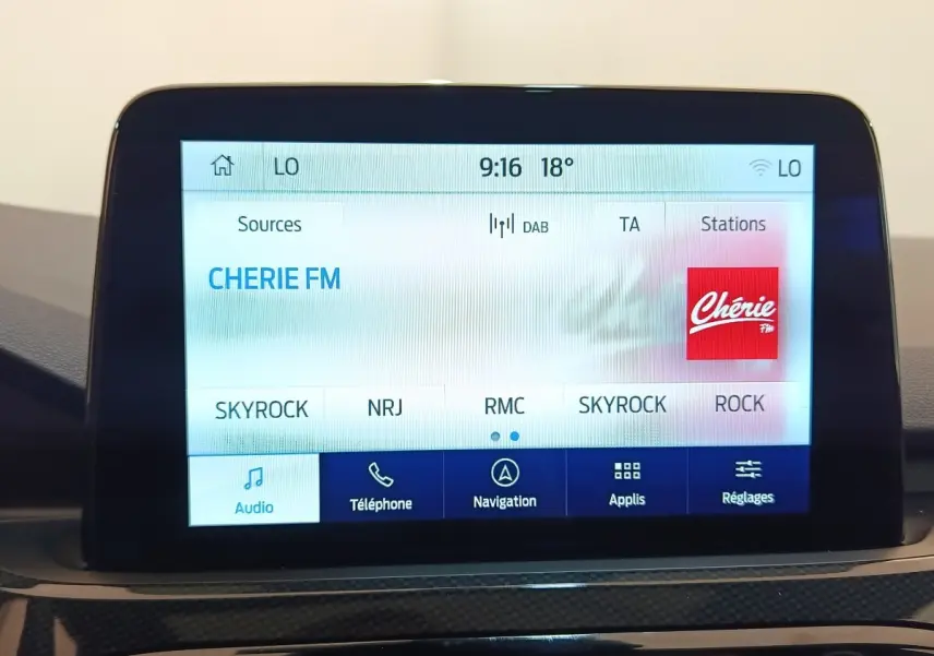 Écran tactile central du Ford Kuga 2023 affichant les stations radio, interface claire en intérieur noir.
