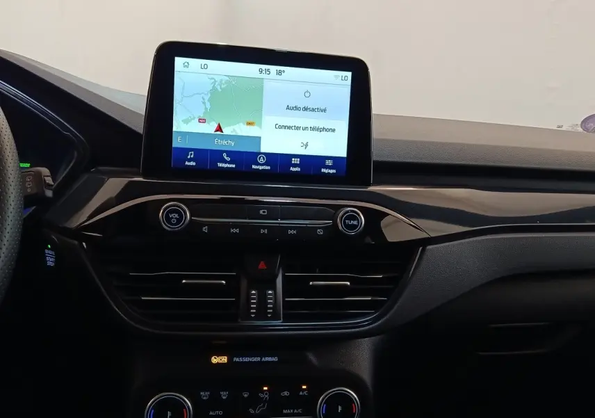 Tableau de bord noir du Ford Kuga 2023 avec écran tactile central affichant la navigation, vu de face.