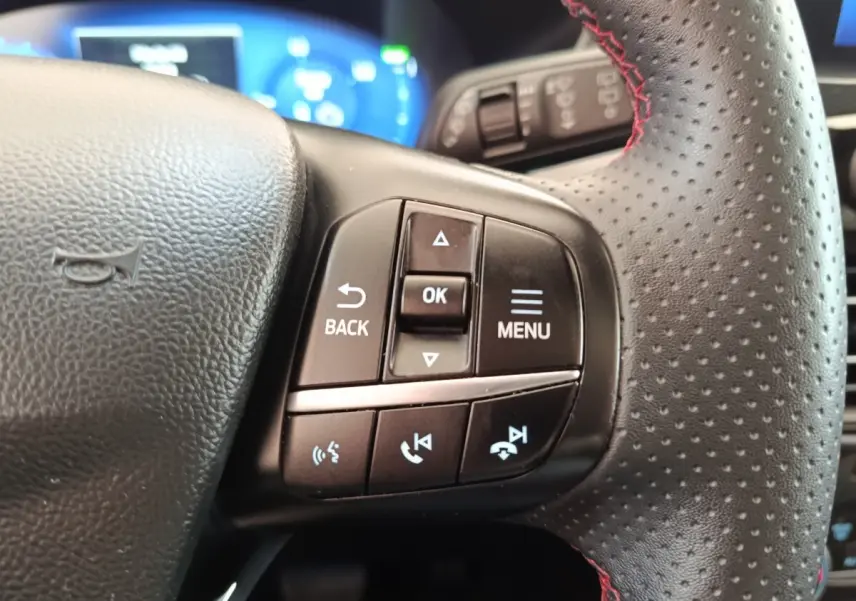 Gros plan sur les commandes multifonctions à gauche du volant en cuir perforé du Ford Kuga gris foncé 2023.