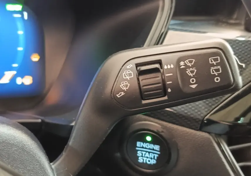 Gros plan sur la commande d’essuie-glace et le bouton start/stop du tableau de bord intérieur du Ford Kuga gris foncé.