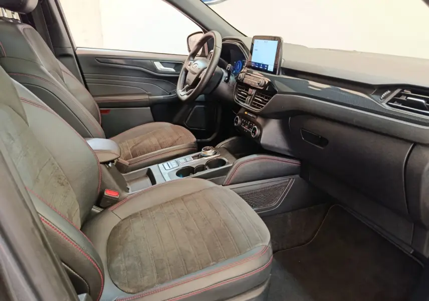 Intérieur avant du Ford Kuga 2023, vue côté gauche, sièges gris avec surpiqûres rouges et écran tactile central.