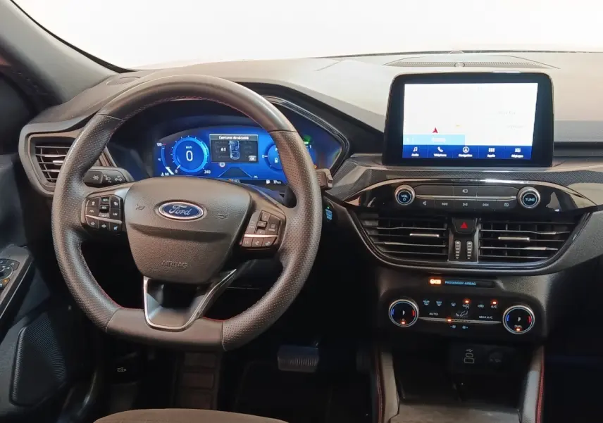 Vue intérieure frontale du tableau de bord du Ford Kuga gris foncé 2023 avec écran tactile central et volant multifonctions.