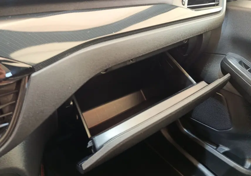 Gros plan sur la boîte à gants ouverte côté passager du Ford Kuga 2.5 Hybrid ST-Line X 2023, intérieur noir.