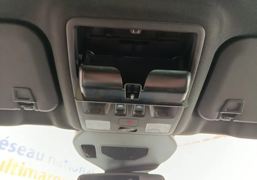 Vue intérieure du plafond de la Ford Kuga gris foncé 2023, montrant le compartiment lunettes et commandes lumineuses.