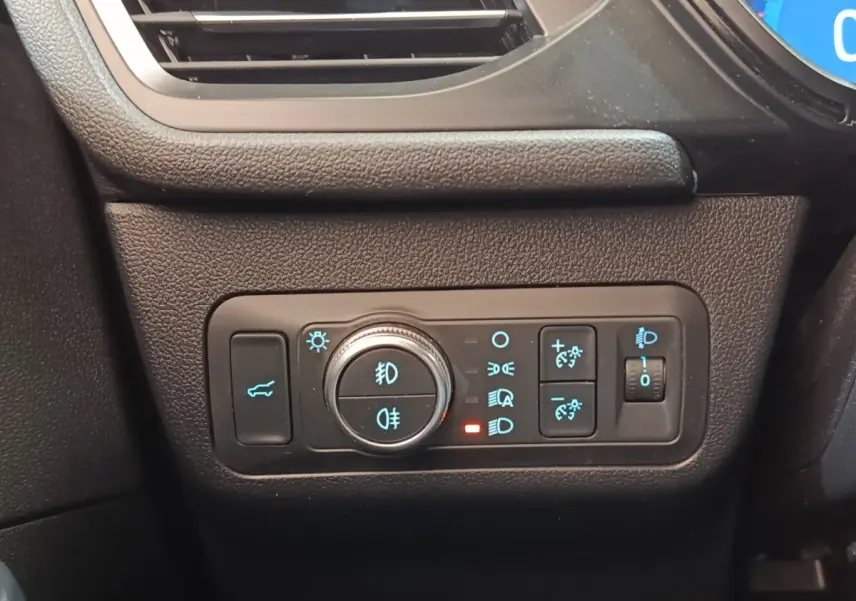 Vue rapprochée du panneau de commandes des feux et du coffre sur le côté gauche du tableau de bord noir du Ford Kuga gris foncé.