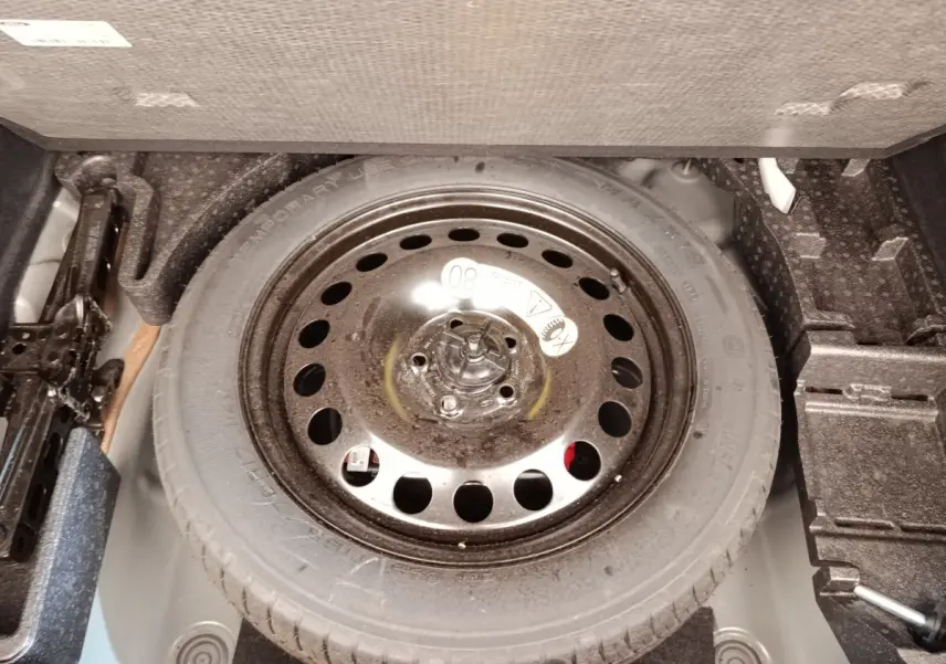Vue rapprochée de la roue de secours noire dans le coffre du Ford Kuga gris foncé 2023.